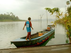 A man on a long-tailed boat at the Cheow Lan Lake (Rajjaprabha Dam).